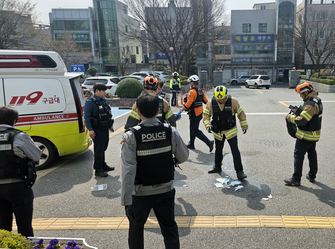 Firefighters on Thursday clean up the parking lot in front of the National Tax Service's Dongulsan District Office after a man attempted self-immolation.  (Yonhap)