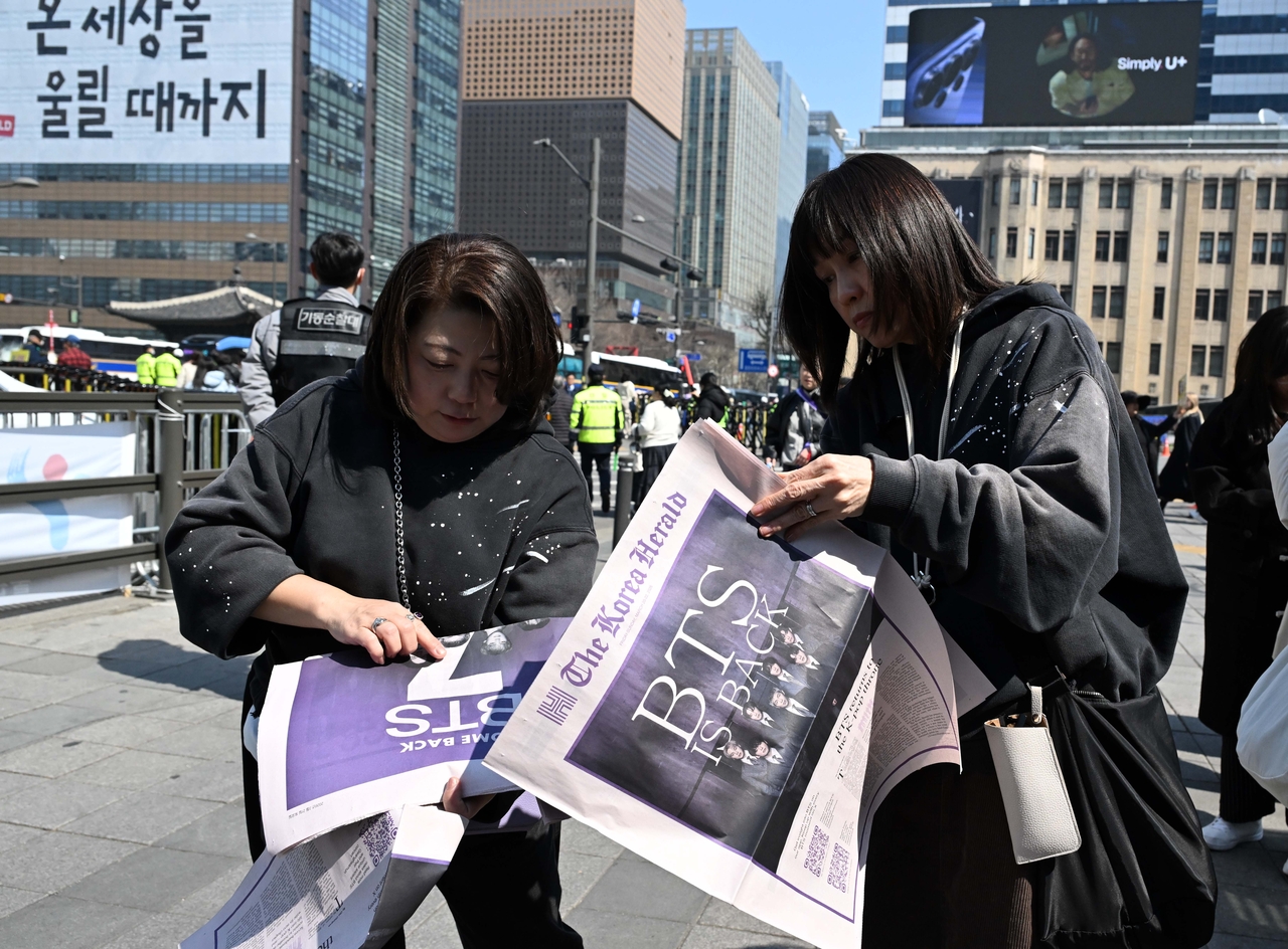 BTS fans on March 21 read The Korea Herald's special edition marking BTS' comeback, before attending the concert at Gwanghwamun Square in Seoul. (Lee Sang-sub/The Korea Herald)