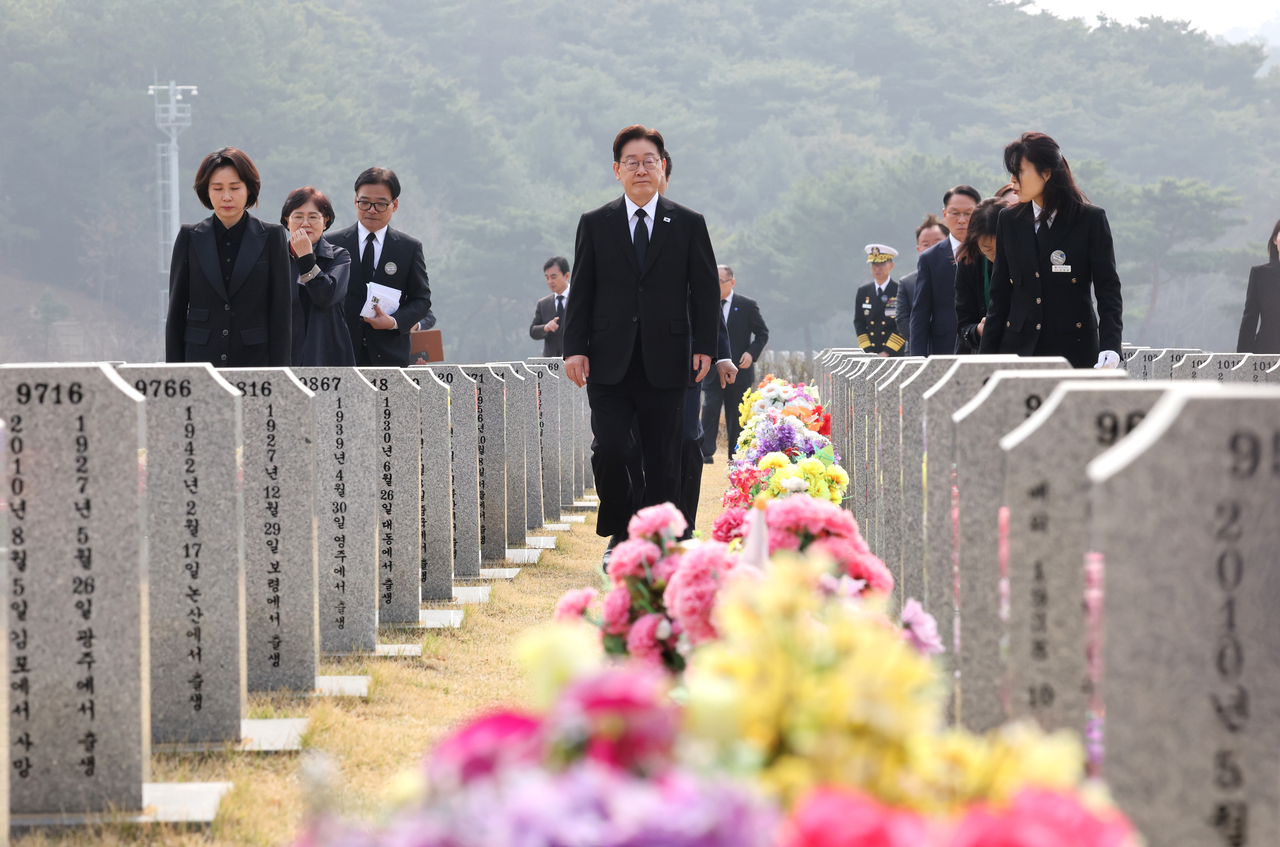 President Lee Jae Myung (center) leaves after paying respects at the grave of the late Warrant Officer Han Ju-ho at Daejeon National Cemetery on Friday. (Yonhap)