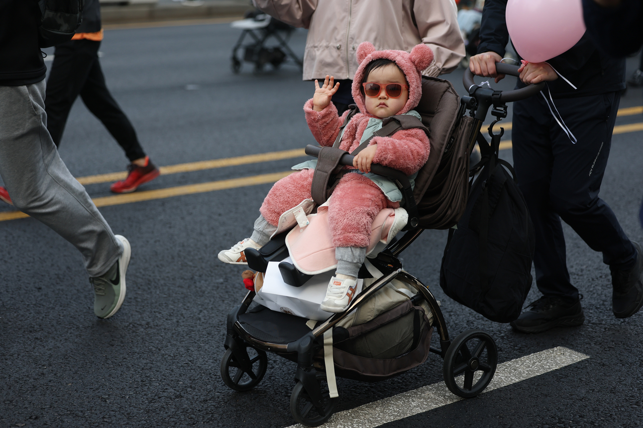 A toddler waves from a stroller during the 2026 Seoul Stroller Run on Saturday. (Yonhap)