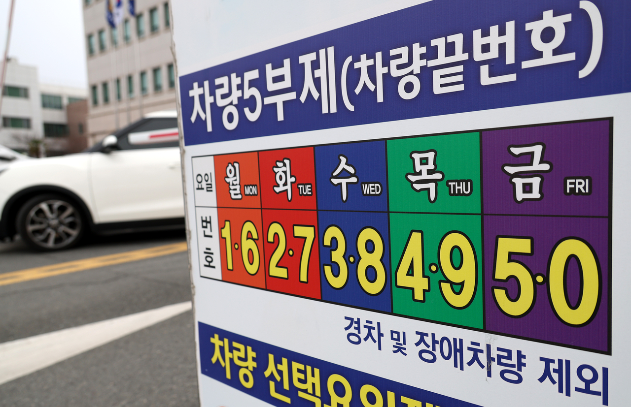 A sign informing drivers of the public-sector five-day driving restriction system is posted at the parking lot of a police station in Changwon, South Gyeongsang Province, Wednesday. Under the measure, cars are divided into five groups based on their license plate numbers and each group is prohibited from driving on a designated weekday. (Yonhap)