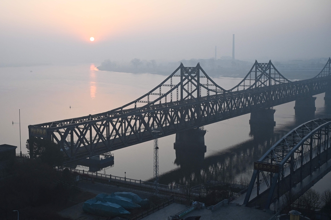 The sun rises over the North Korean town of Sinuiju, behind the Sino-Korean Friendship Bridge (left) and the Yalu River Broken Bridge (right), as seen from the border city of Dandong, in China's northeast Liaoning province on Thursday. (AFP-Yonhap)