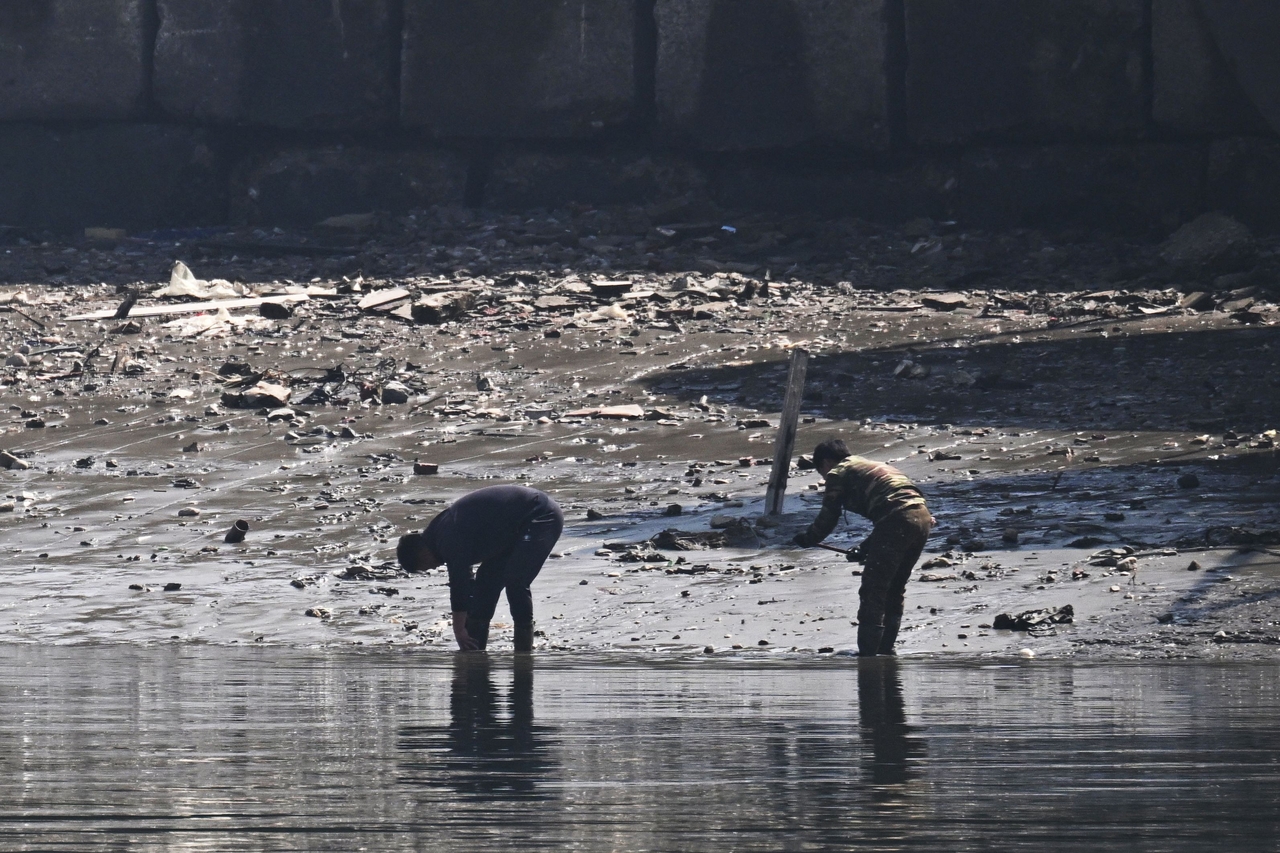 North Korean men are seen on the bank of the Yalu River in the North Korean town of Sinuiju, opposite the border city of Dandong, in China's northeast Liaoning province, Thursday. (AFP-Yonhap)
