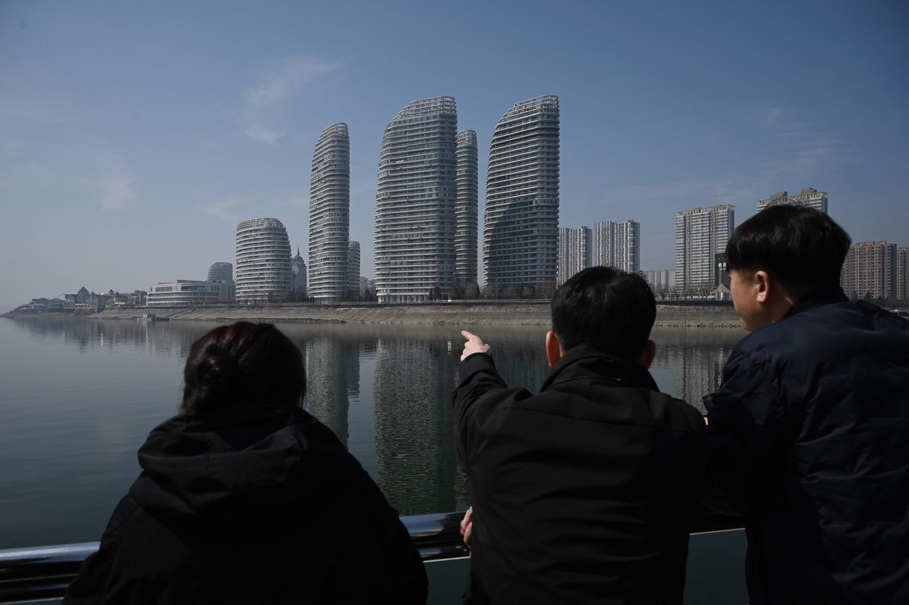 People look at buildings in the border city of Dandong, in China's northeast Liaoning province while on a boat tour on the Yalu river, Thursday. (AFP-Yonhap)