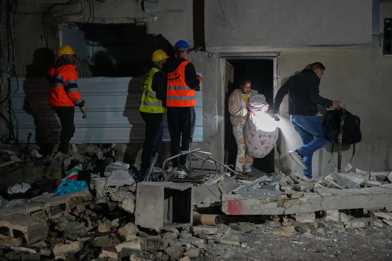 Residents carry personal belongings as they leave a building damaged in a missile strike in Tel Aviv, Israel, Saturday. (AP-Yonhap)