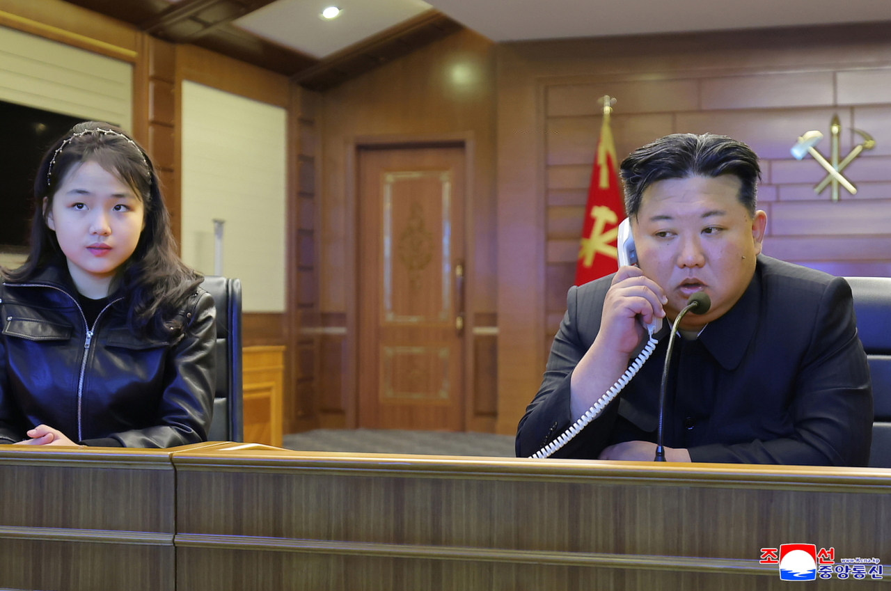 A photo released by the official Korean Central News Agency shows North Korean leader Kim Jong-un (right) and his daughter Kim Ju-ae watching a live feed of a strategic cruise missile test-fire from the naval Destroyer Choe Hyon at an undisclosed location in North Korea, March 10. (EPA-Yonhap)