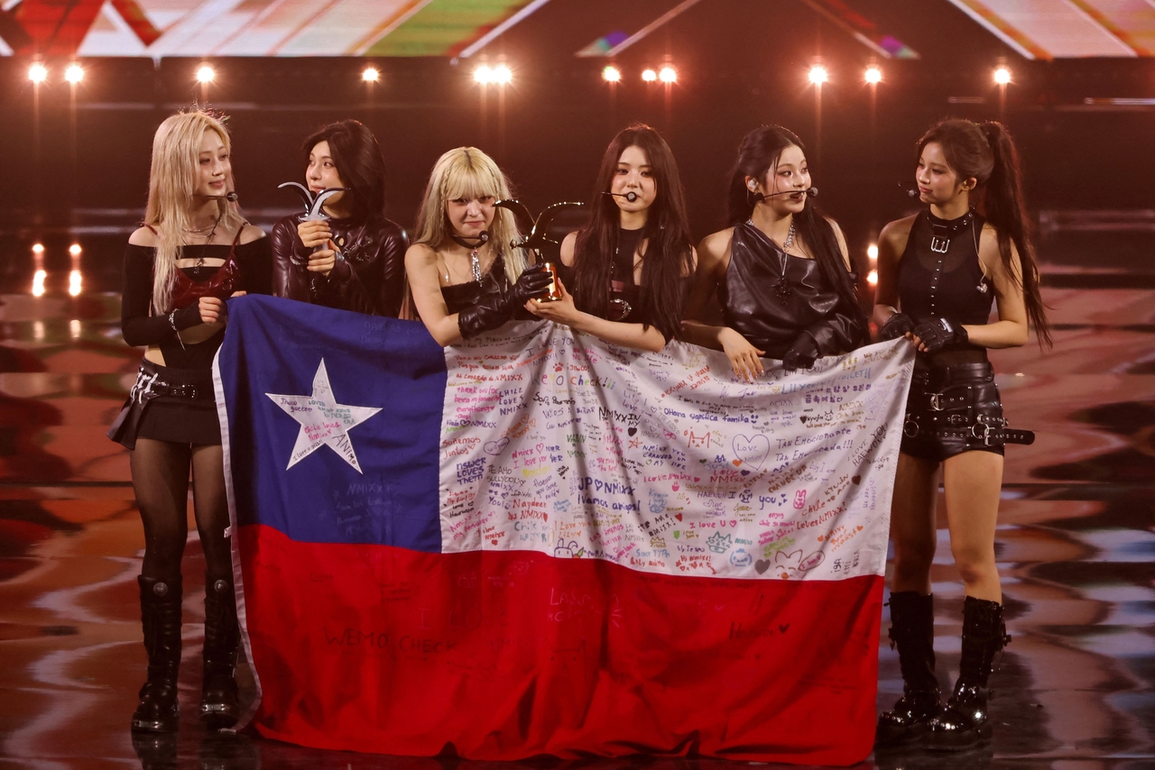 K-pop group Nmixx holds a Chilean national flag signed by fans during the 65th Vina del Mar International Song Festival in Vina del Mar, Chile, February 25, 2026. (Photo by Javier TORRES / AFP)