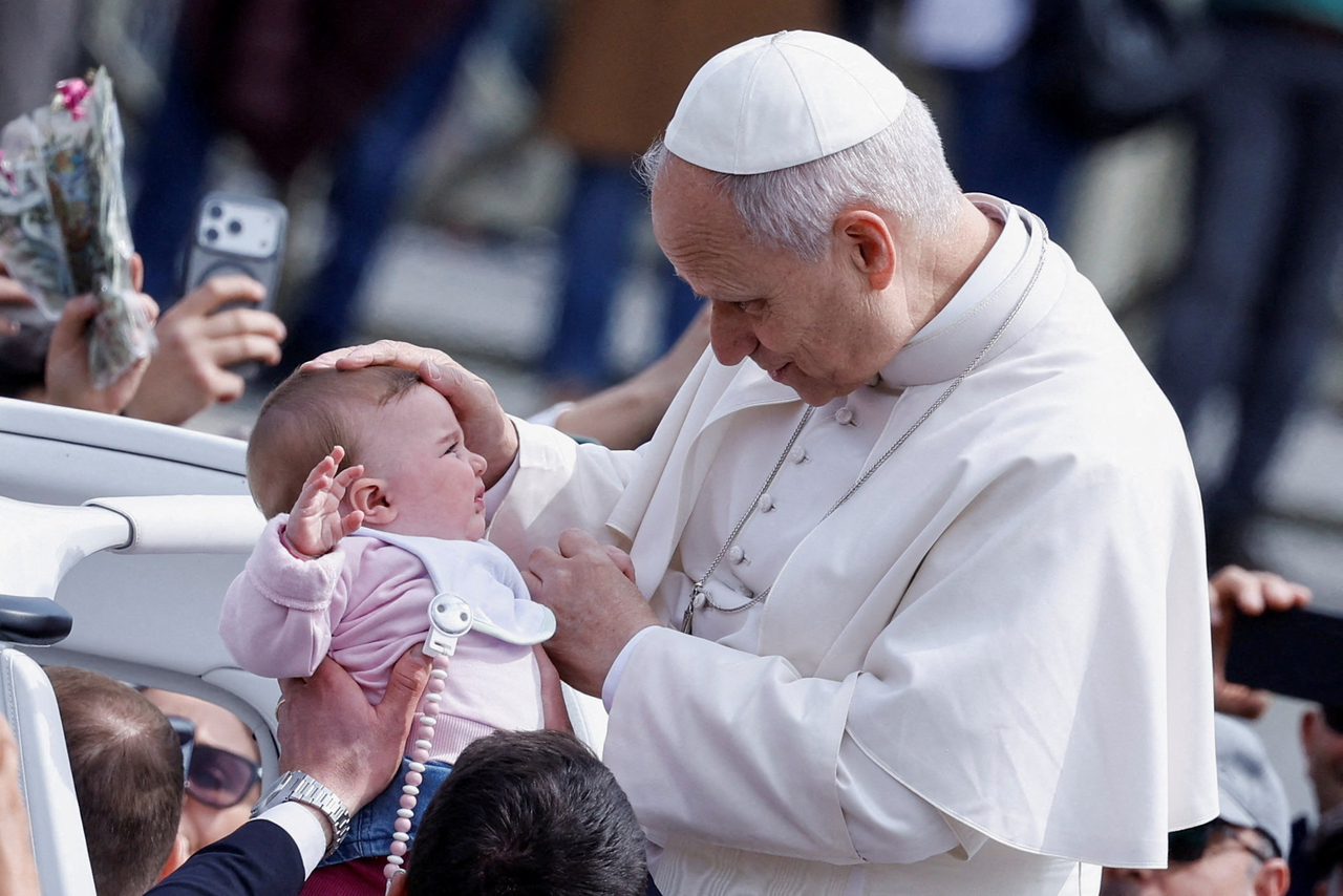 Pope Leo XIV blesses a baby as he leaves after Palm Sunday Mass in St. Peter’s Square at the Vatican, Sunday.    (Reuters-Yonhap)