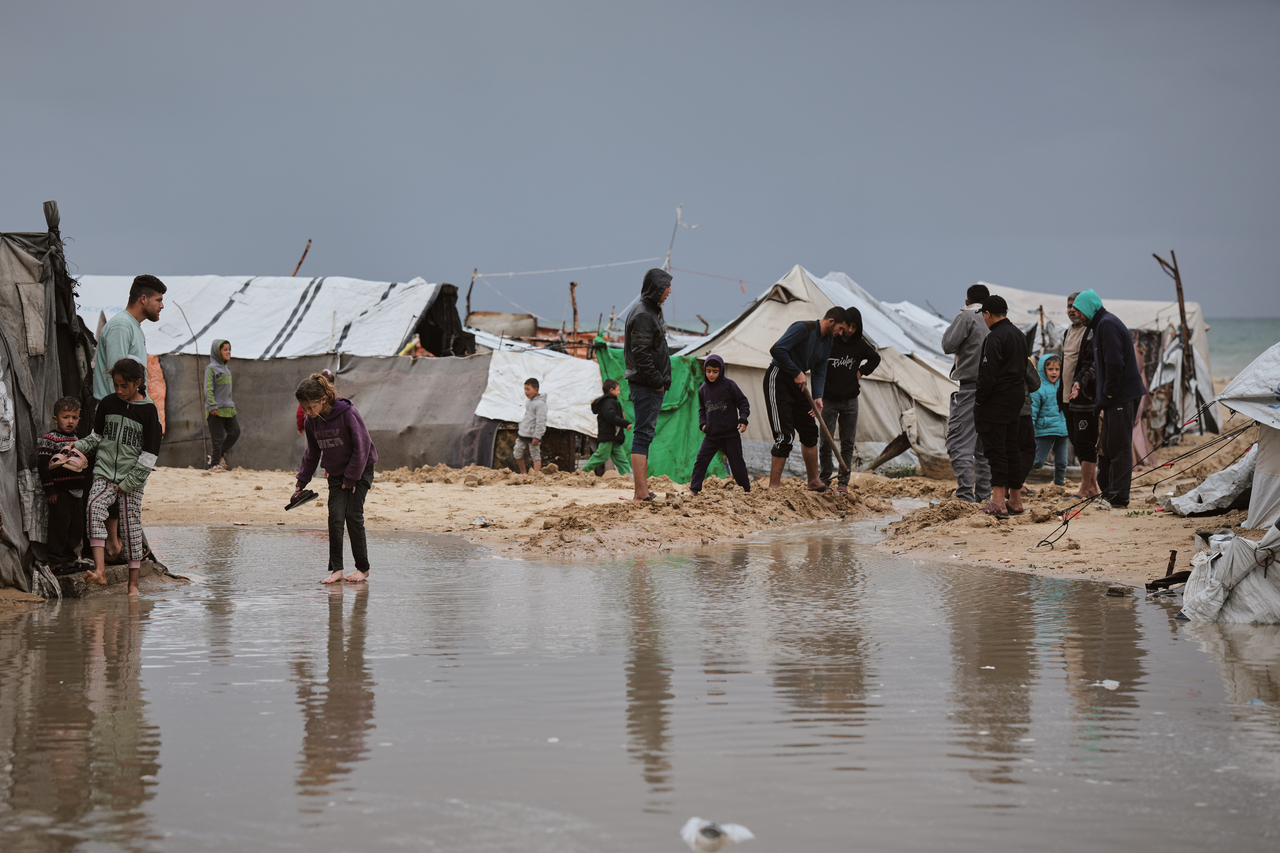 Palestinians walk through a flooded area in a temporary tent camp after heavy rainfall in Gaza City, Thursday. (AP via Yonhap)