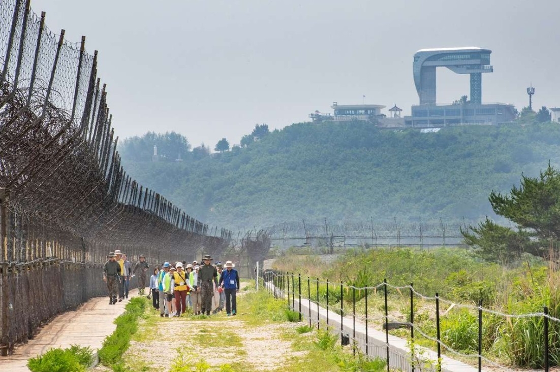 Hikers meander along a trail set near barbed-wire fences close to the Military Demarcation Line on the DMZ Peace Trail. (Defense Ministry)