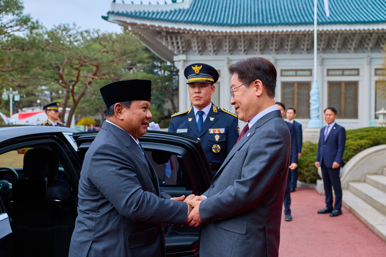 President Lee Jae Myung (right) welcomes Indonesian President Prabowo Subianto upon his arrival for a state visit at Cheong Wa Dae on Wednesday. (Cheong Wa Dae via Yonhap)