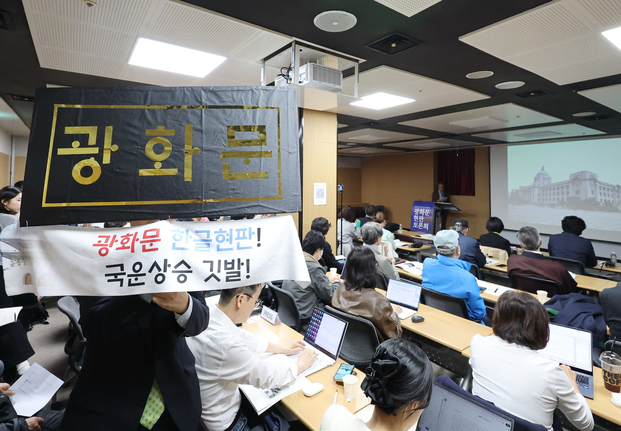 An attendee holds a placard bearing a Hangeul Gwanghwamun sign at a forum on the gate’s signboard at the National Museum of Korean Contemporary History in Jongno-gu, Seoul, on March 31. The forum was organized to discuss key positions and arguments regarding the possible addition of a Hangeul signboard. (Yonhap)