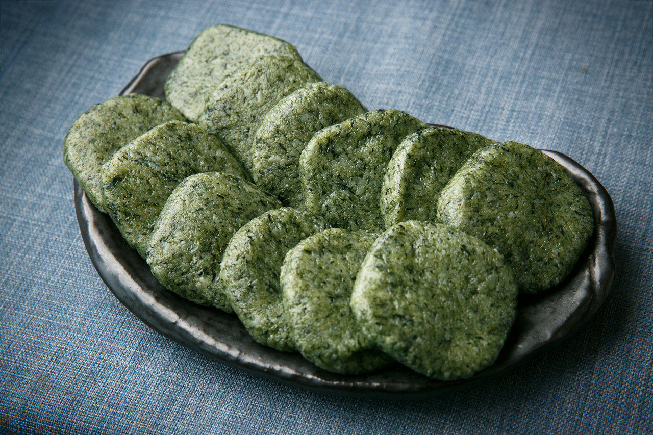 Ssuk mugwort rice cake sliced on a plate showing bright green interior from freshly harvested Korean mugwort