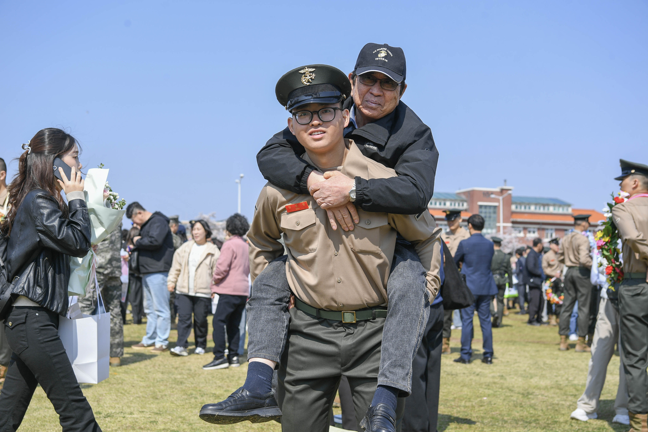 Pvt. Kim Jun-young (front) carries his grandfather, who also was a Marine, on his back for a commemorative photo during the graduation ceremony for the 1,327th recruit class held in Pohang, North Gyeongsang Province, Thursday. (Yonhap)