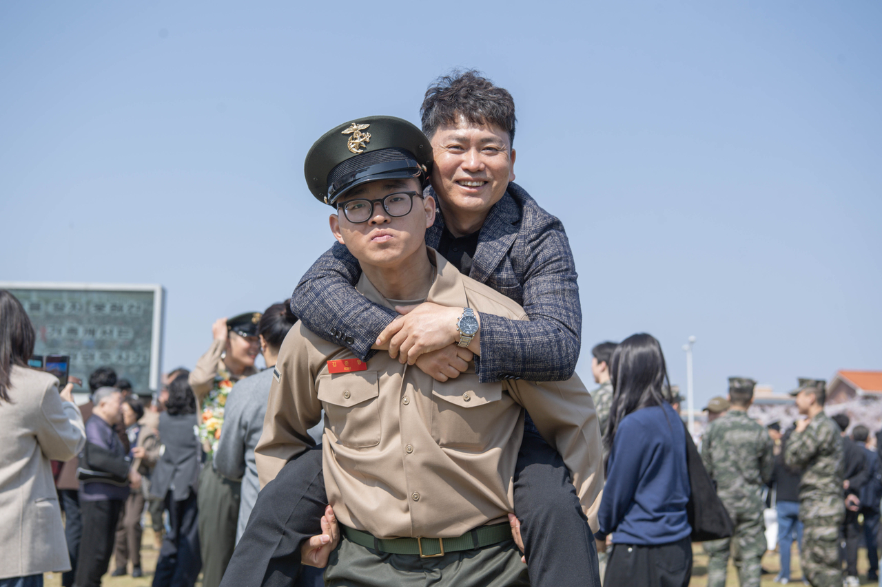 Pvt. Kim Jun-young (front) carries his father, who also was a Marine, on his back for a commemorative photo during the graduation ceremony for the 1,327th recruit class held in Pohang, North Gyeongsang Province, Thursday. (Yonhap)