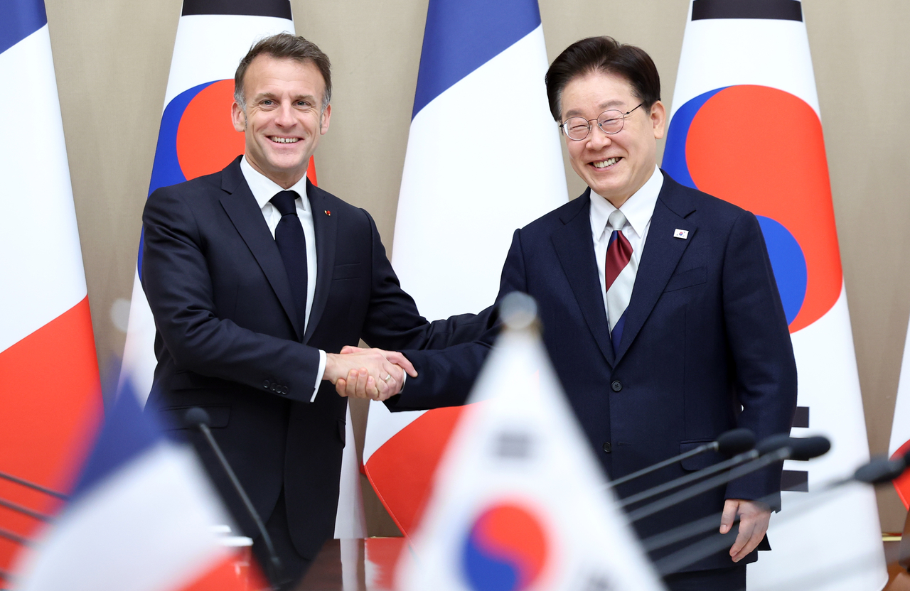 South Korean President Lee Jae Myung (right) and French President Emmanuel Macron shake hands ahead of their talks at the presidential office Cheong Wa Dae in Seoul on Friday. (Yonhap)