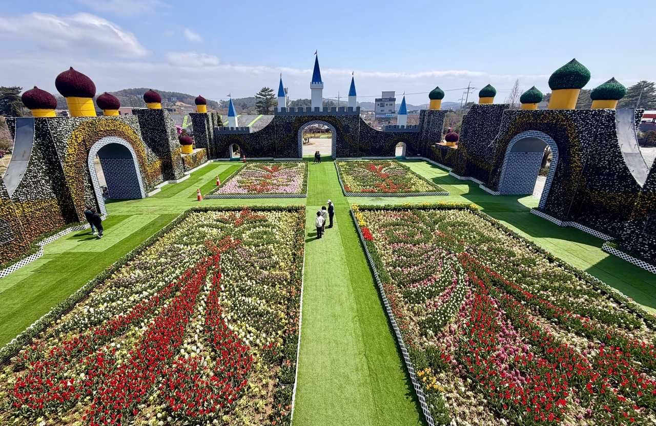 Visitors walk through geometric tulip gardens flanked by a flower-covered castle installation at the 2026 World Tulip Festival in Taean, South Korea, on Saturday. (Courtesy of the World Tulip Festival organizing committee)