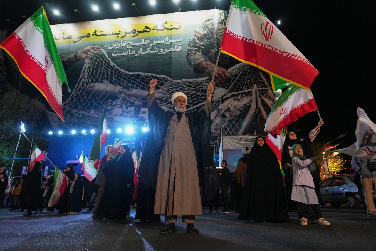 A Shiite cleric holds an Iranian flag during a pro-government gathering in a square in Tehran, Iran, Sunday, April 5, 2026. (AP)