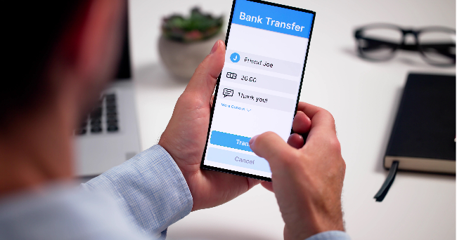 A stock photo shows a person making an online transfer of funds via a smartphone. (123rf)