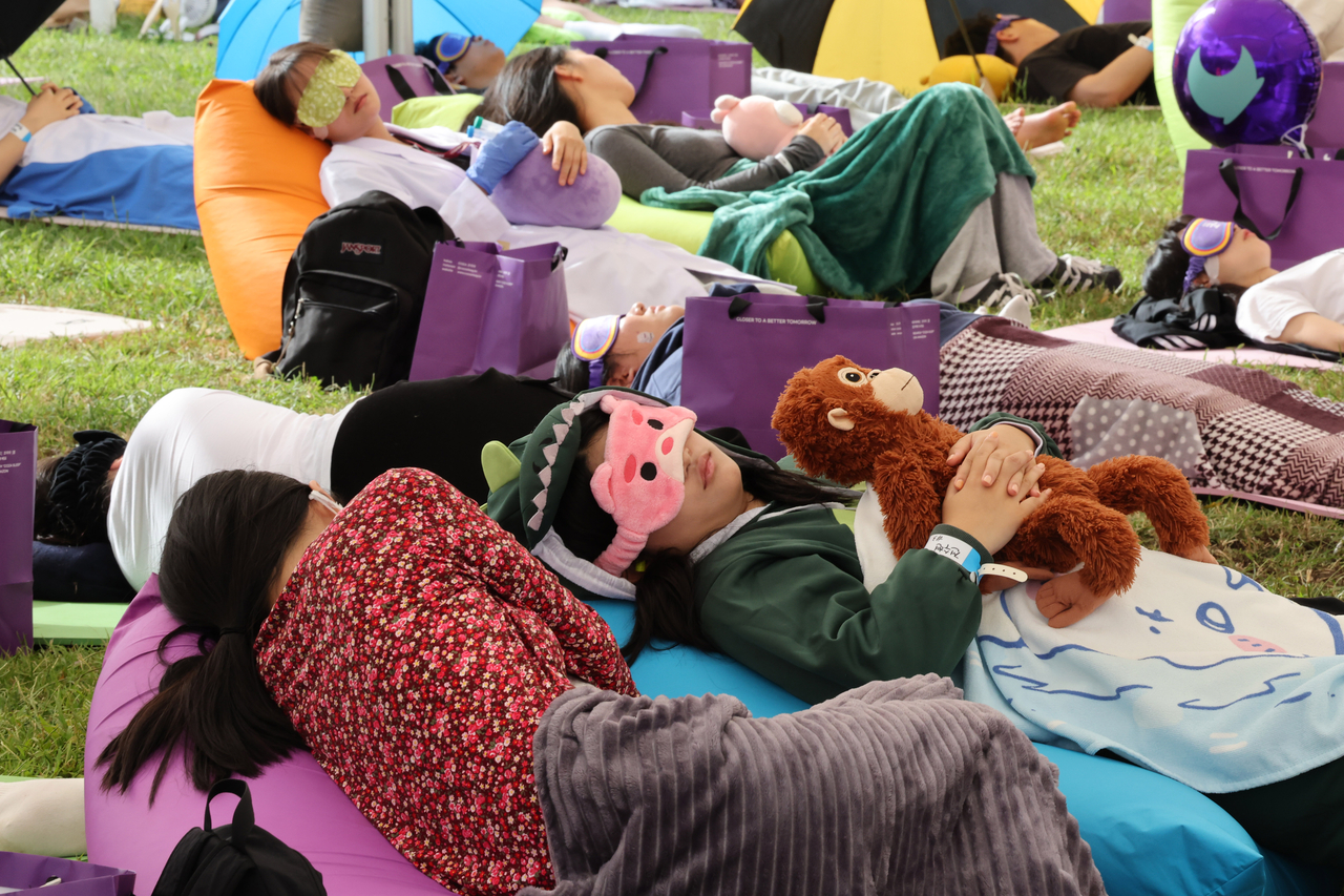 Participants take a nap during the 2025 Hangang Nap Competition at Yeouido Hangang Park in Seoul on April 20, 2025. (Newsis)