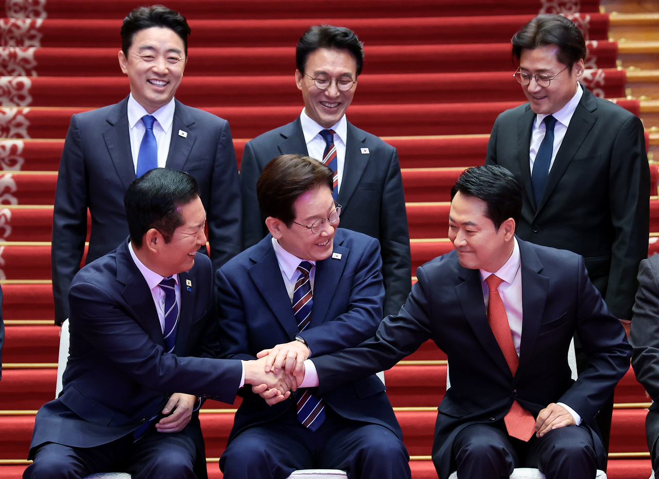 President Lee Jae Myung holds hands with Democratic Party Chair Jung Chung-rae and People Power Party Chair Jang Dong-hyeok during a photo session ahead of a consultative meeting among the government and rival parties on livelihoods and the economy at Cheong Wa Dae on Tuesday. In the back row, from left, are presidential chief of staff Kang Hoon-sik, Prime Minister Kim Min-seok and senior presidential secretary for political affairs Hong Ihk-pyo. (Yonhap)