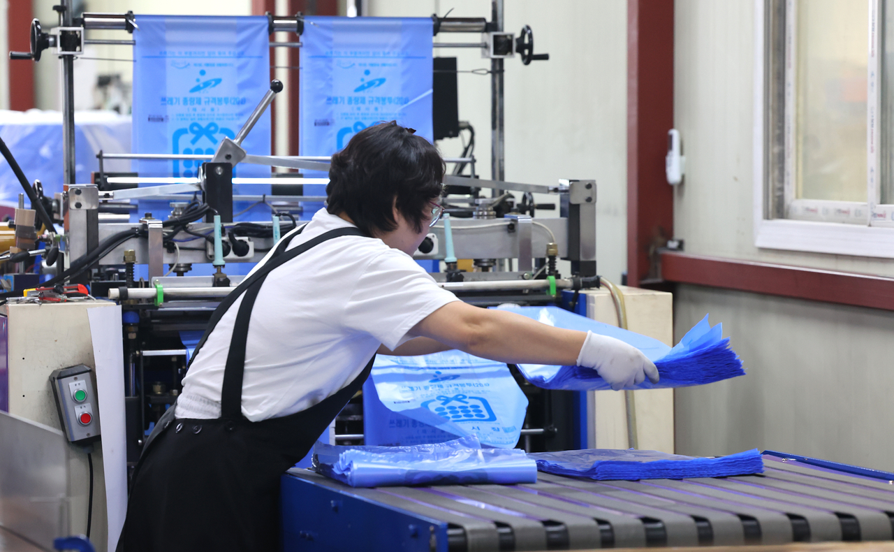An employee stacks official South Korean trash bags produced at a factory in Incheon on Thursday, amid reported stockpiling of the bags due to fears of supply disruptions caused by the Middle East war. (Yonhap)