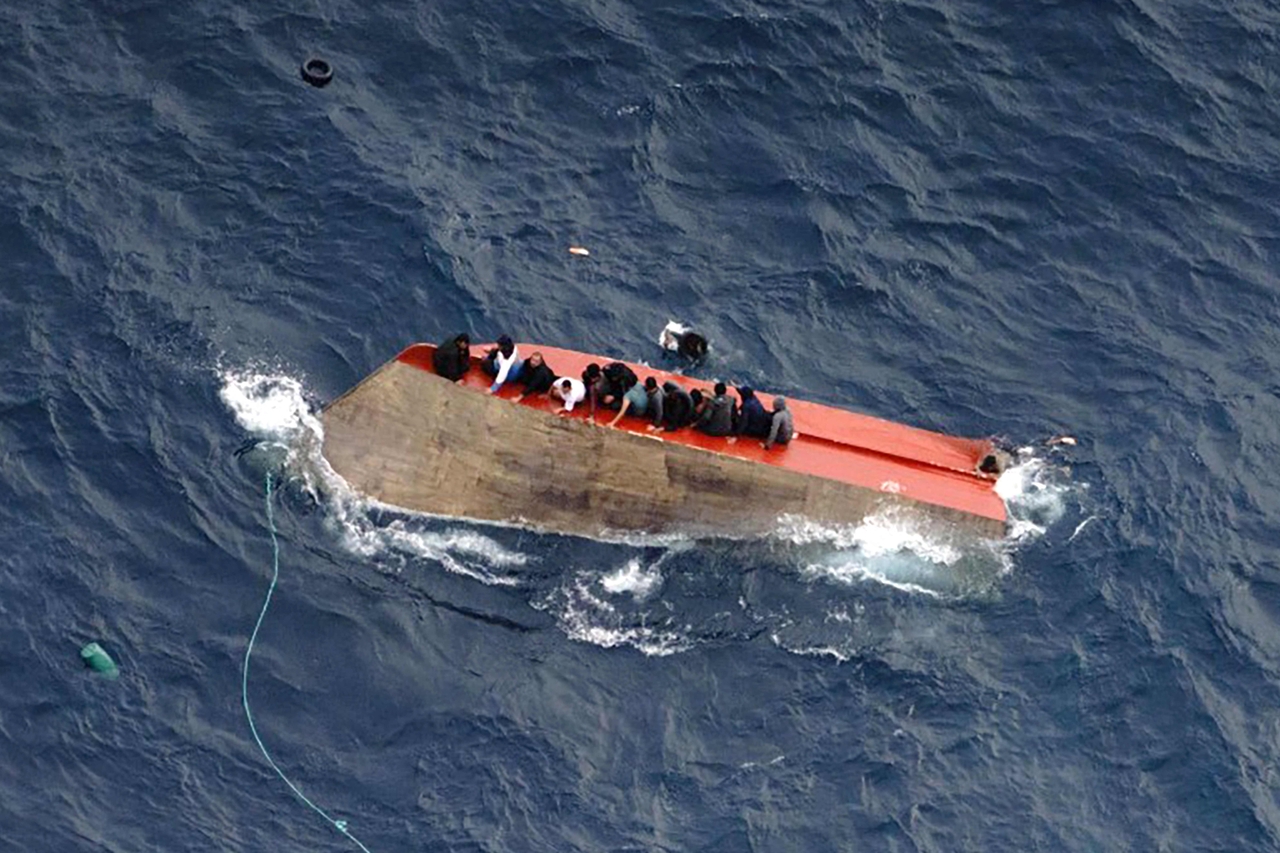 Migrants seatted on a capsized boat off on Saturday. (AFP-Yonhap)
