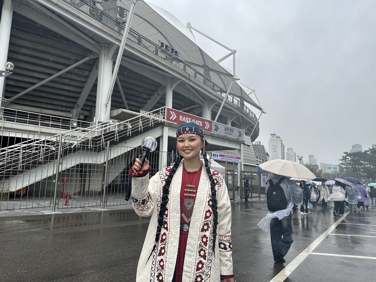 Venera, a BTS fan from Kazakhstan, holds an Army Bomb while wearing traditional Kazakh clothing in red and white — colors associated with BTS’ latest album 'Arirang' — in front of Goyang Stadium, Thursday. (Lee Jung-joo/The Korea Herald)