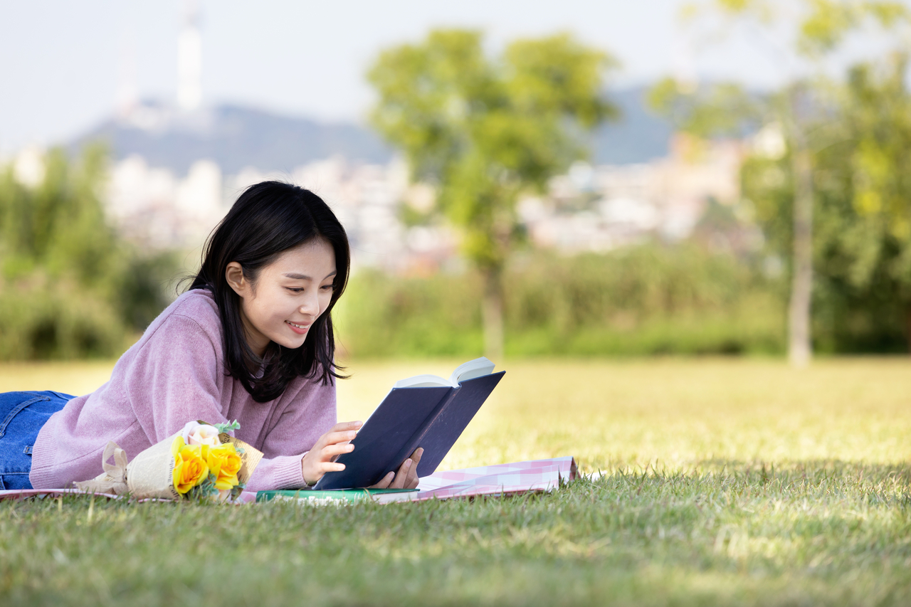 A woman reads a book in a Han River park. (Getty Image)