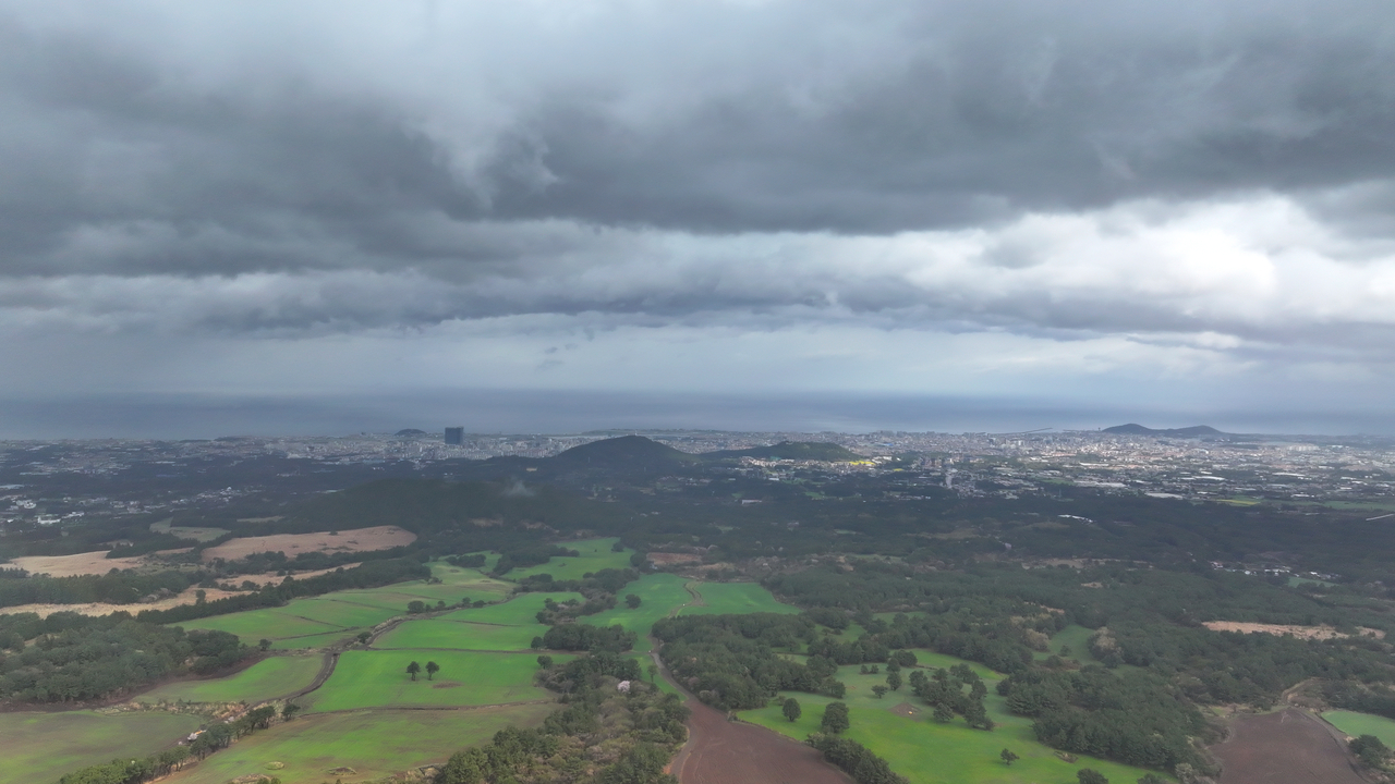 Thick rain clouds blanket Jeju City, Jeju Island, as seen from the mid-mountain area of Ora-dong, on Thursday. (Yonhap)