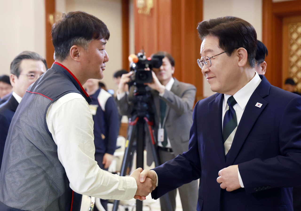 President Lee Jae Myung (right) shakes hands with Yang Kyung-soo, president of the Korea Confederation of Trade Unions, during a meeting at Cheong Wa Dae in central Seoul on Friday. (Yonhap)