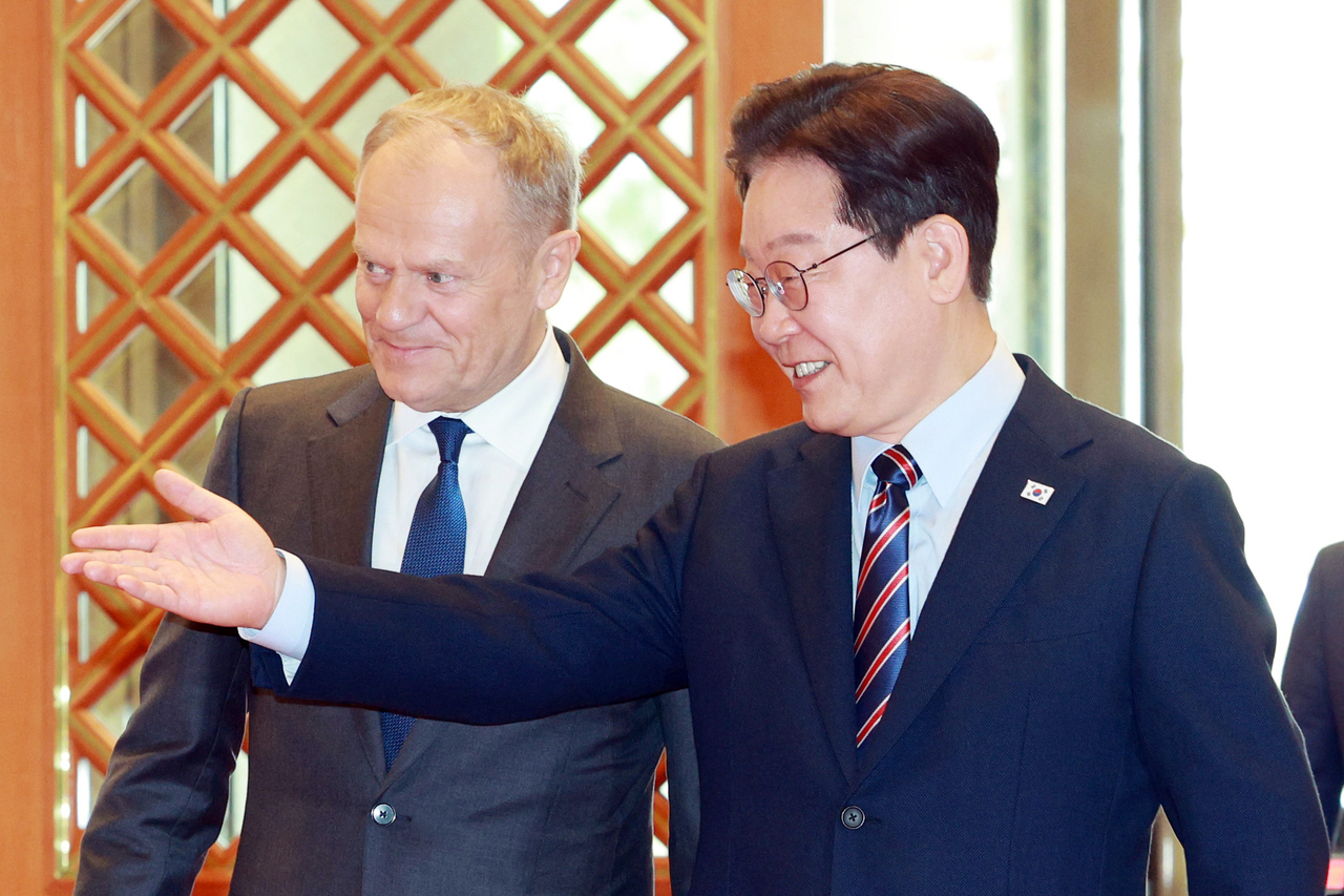 President Lee Jae Myung (R) and Polish Prime Minister Donald Tusk head to the venue for their summit at Cheong Wa Dae in Seoul on Monday. (Yonhap)