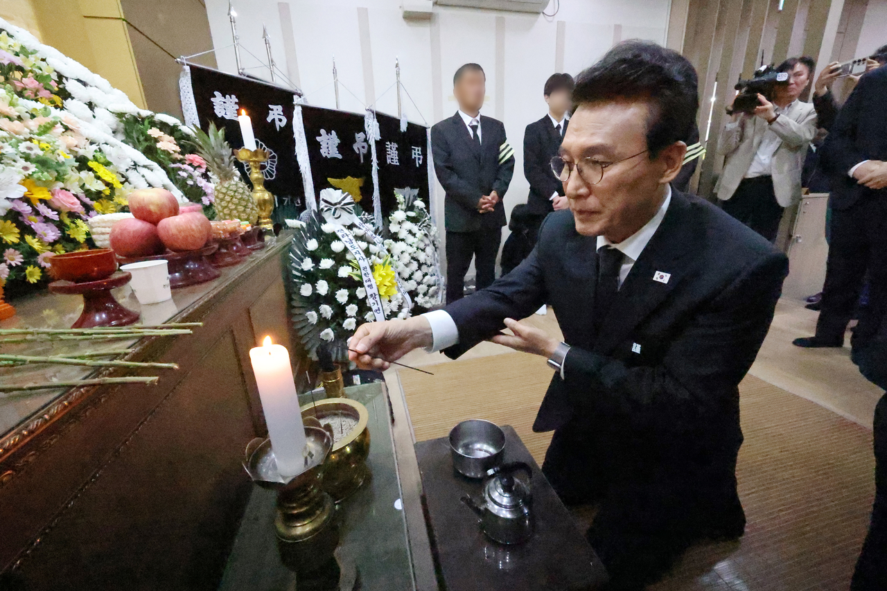 Prime Minister Kim Min-seok lights incense while paying his respects to two firefighters killed in a warehouse fire the previous day, at a funeral home in the southwestern county of Wando on Monday. (Yonhap)