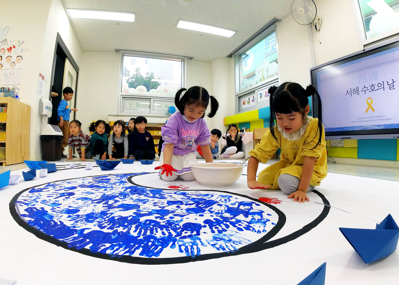In this unrelated photo, children at a day care center in Gwangju draw a large Korean flag on March 26. (Yonhap)