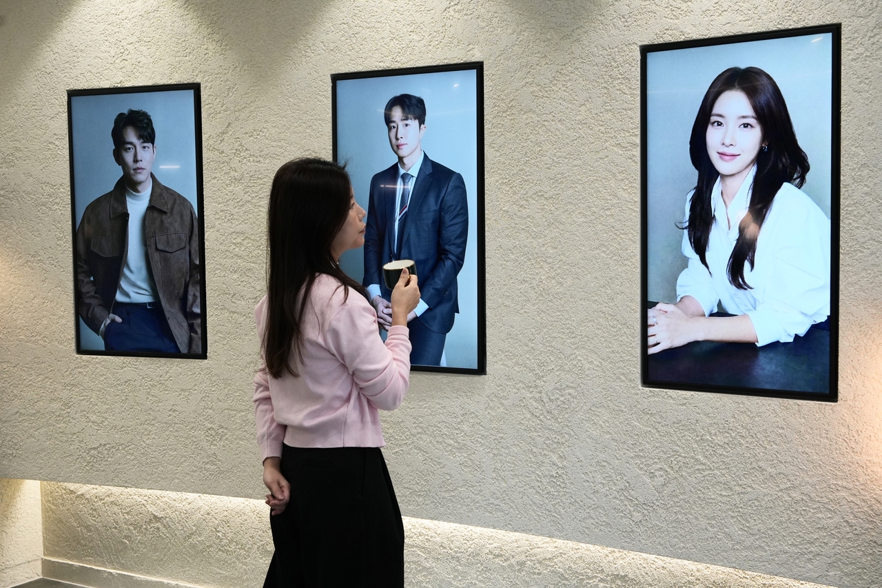 At a recent matchmaking event hosted by Gentlys in Seoul, a woman browses photos of other participants displayed in large frames and hung on a wall. (Gentlys)