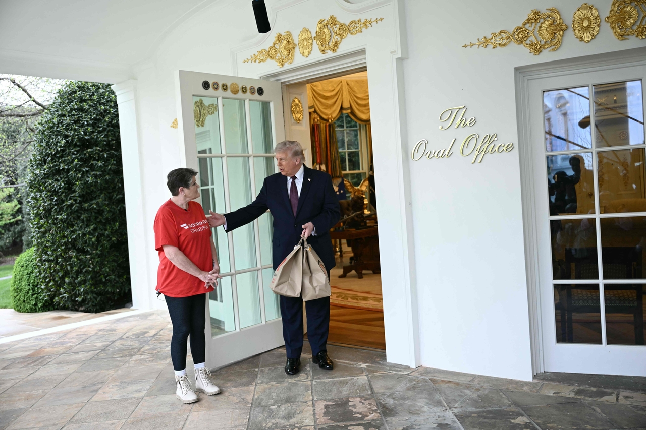 US President Donald Trump (right) receives a Doordash delivery worker Sharon Simmons after she delivered McDonald's outside of the Oval Office at the White House, in Washington, Monday.    (AFP-Yonhap)