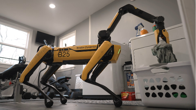 Spot, Boston Dynamics’ four-legged robot, picks up clothes and places them in a laundry basket in a demonstration video released Tuesday. (Hyundai Motor Group)