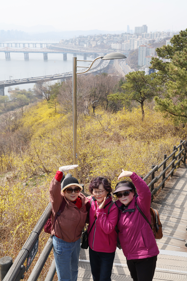 Three women pose for a photo along a hiking trail on Eungbongsan in Seongdong-gu, Seoul, on March. 24. (Yonhap)