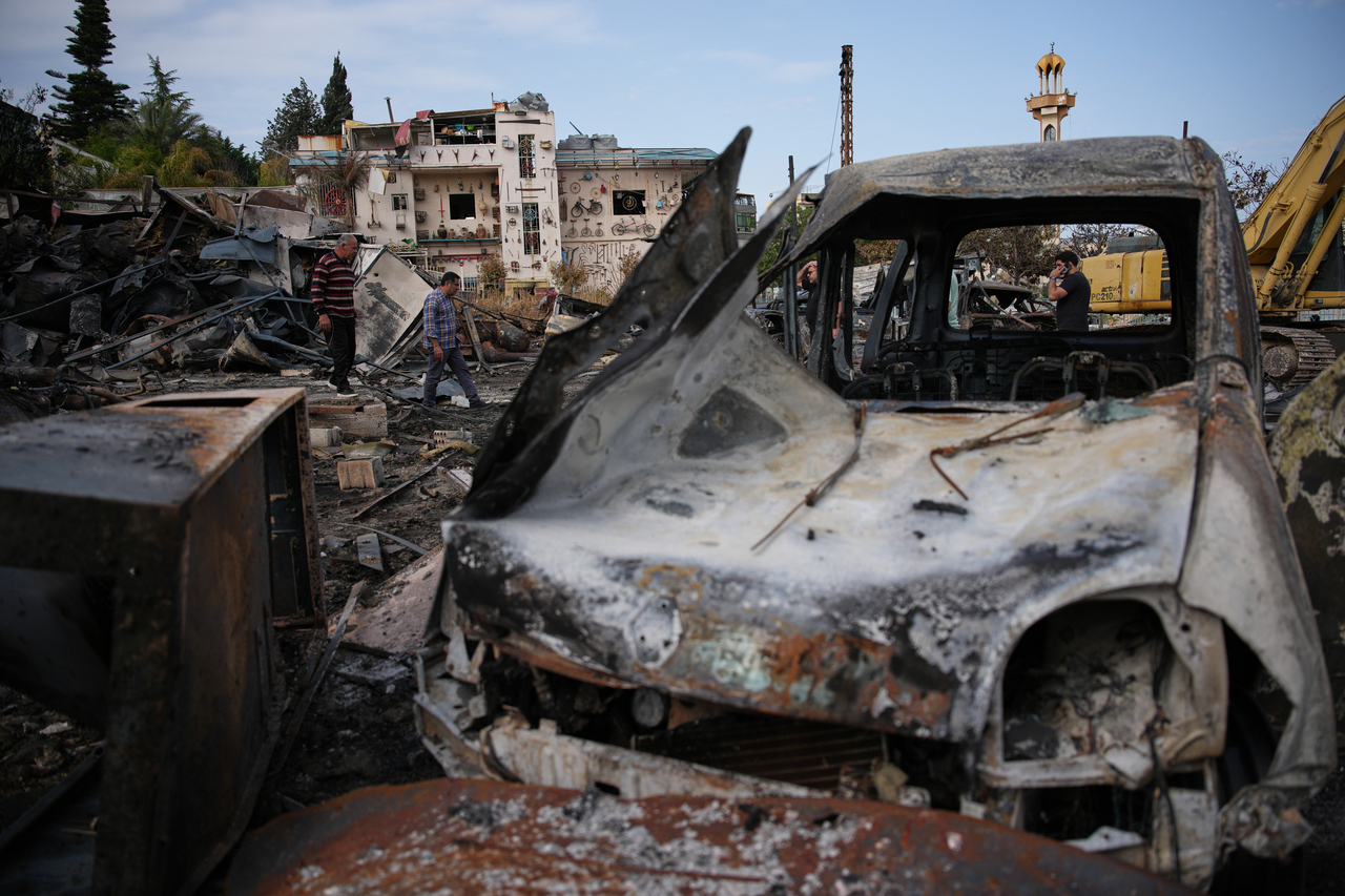 Locals walk among vehicles burned in an Israeli airstrike in Jibchit, southern Lebanon, Friday, following a ceasefire between Israel and Hezbollah. (AP)