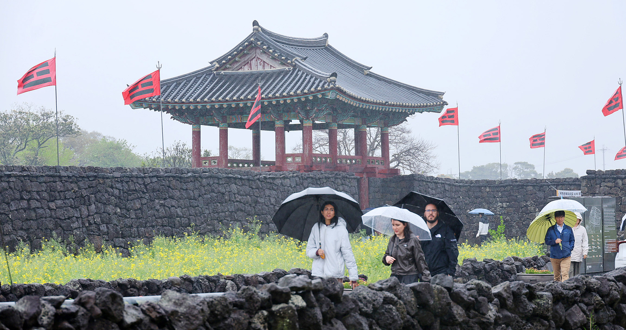 Visitors walk past a pavilion and stone walls at Seongeup Folk Village in Seogwipo, Jeju, on Saturday. (Yonhap)