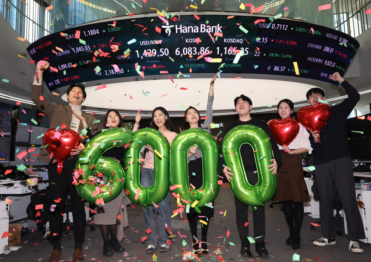 Employees celebrate the Kospi surpassing 6,000 points for the first time at Hana Bank's Seoul dealing room. (Yonhap)