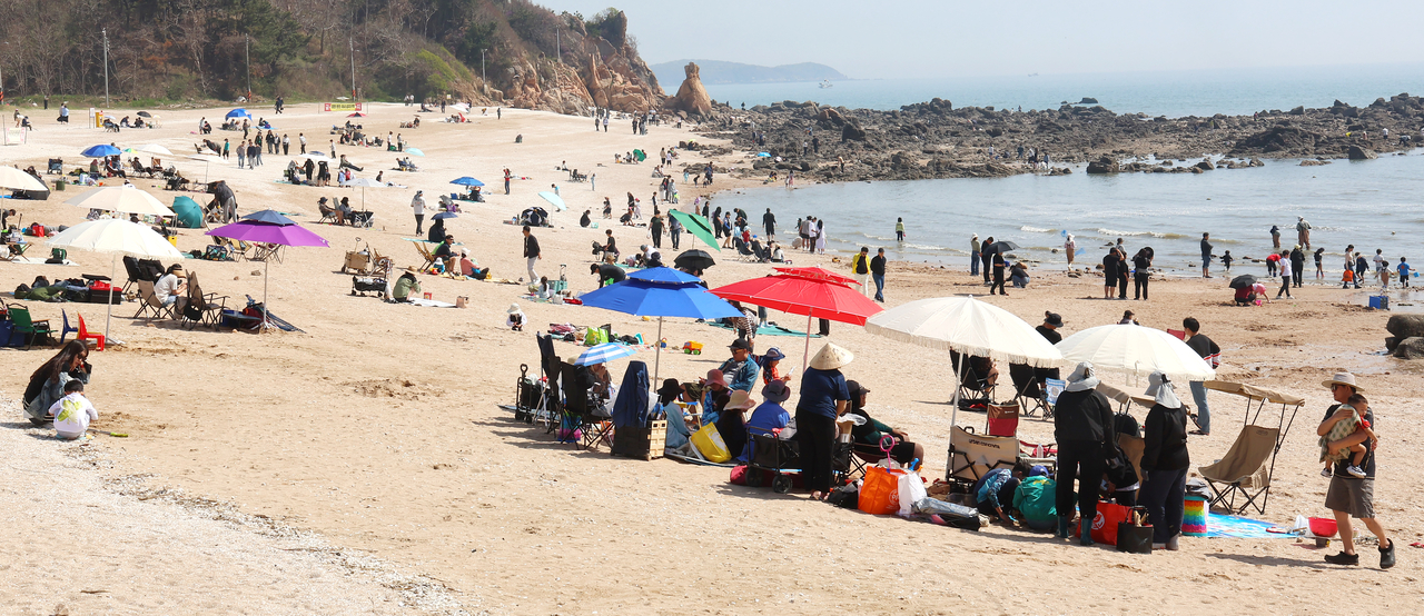 People visit Seonnyeobawi Beach in Incheon on Sunday as Korea is hit by an unseasonal heat wave. (Yonhap)