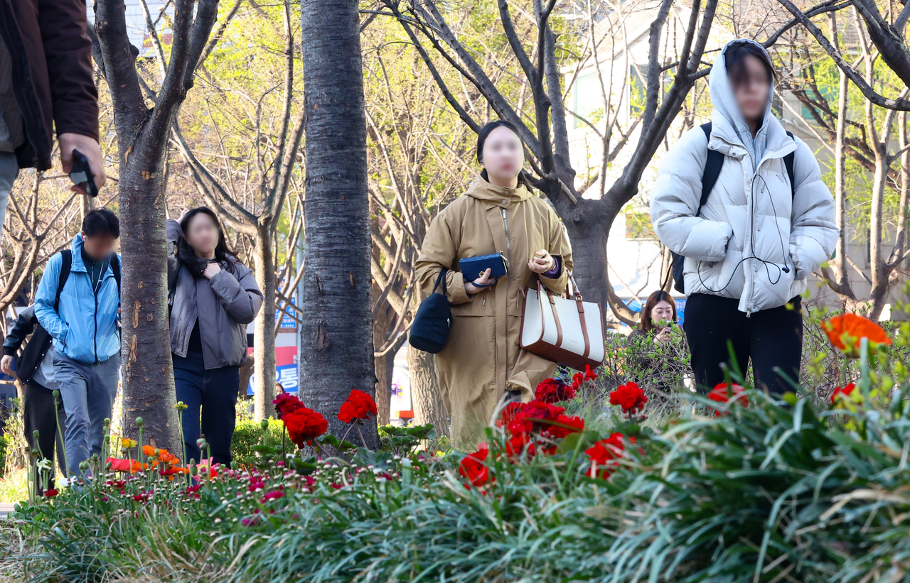 Pedestrians wearing thick jackets walk along a street in Seoul on April 8. (Newsis)
