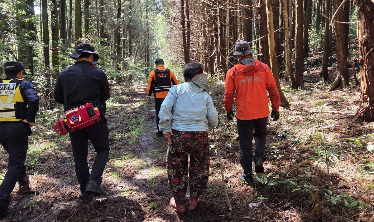 Firefighters rescue a woman in her 60s who became lost while gathering bracken in a forest in Pyoseon-myeon, Seogwipo, on Jeju Island, Sunday. (Jeju Fire and Safety Headquarters)