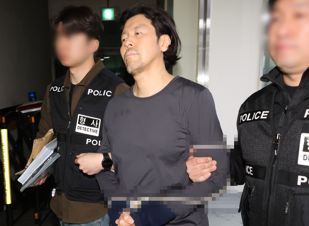 Kim Dong-hwan (center), accused of killing an airline captain, is escorted to a police vehicle at Busanjin Police Station in Busan for transfer to prosecutors on March 26. (Newsis)
