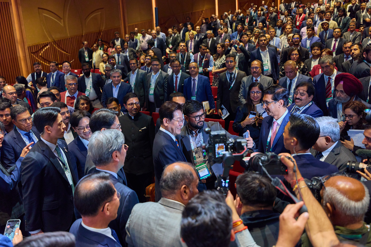 President Lee Jae Myung poses with an Indian businessperson for photos while leaving the Korea-India Business Forum at the Bharat Mandapam Convention Centre in New Delhi on Monday. (Yonhap)