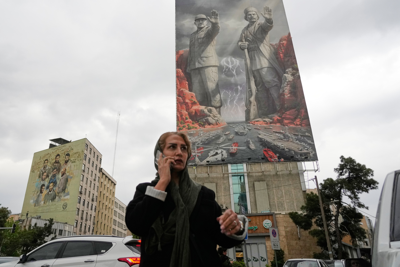 A woman talks on her cellphone as she walks past a billboard showing Iran's national heroes, in Tehran, Iran, Monday. (AP-Yonhap)