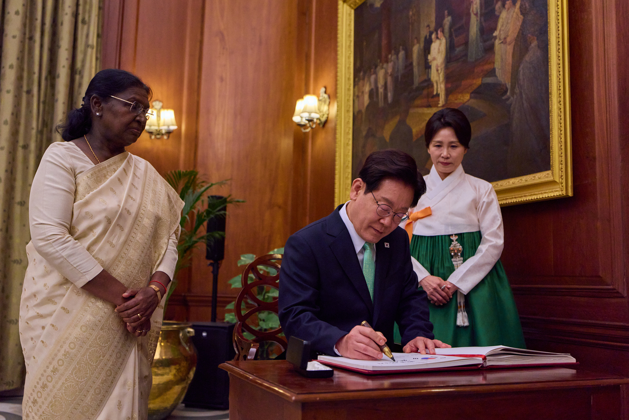 President Lee Jae Myung signs the guest book ahead of a state luncheon hosted by Indian President Droupadi Murmu at Rashtrapati Bhavan (left) in New Delhi Monday. (Yonhap)