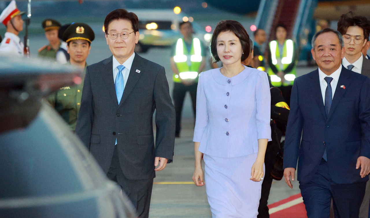 President Lee Jae Myung and first lady Kim Hea Kyung, on a state visit to Vietnam, walk after disembarking from Air Force One upon arrival at Noi Bai International Airport in Hanoi on Tuesday. (Yonhap)