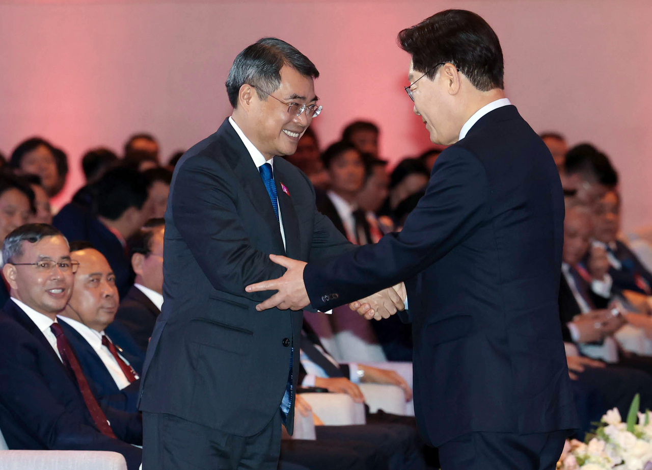 South Korean President Lee Jae Myung (right) shakes hands with Vietnamese Prime Minister Le Minh Hung after delivering remarks at the Korea-Vietnam Business Forum at a hotel in Hanoi on Thursday. (Yonhap)